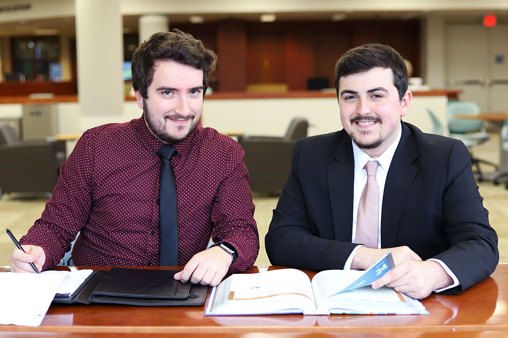 Two young men sitting at a desk.