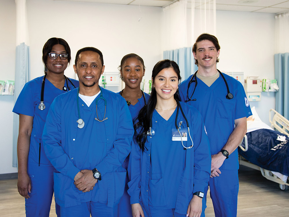 Five students in medical scrubs standing in nursing lab