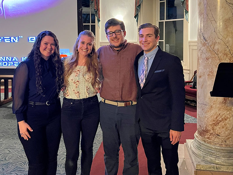 "Love, Moore" Team Four people facing the camera
