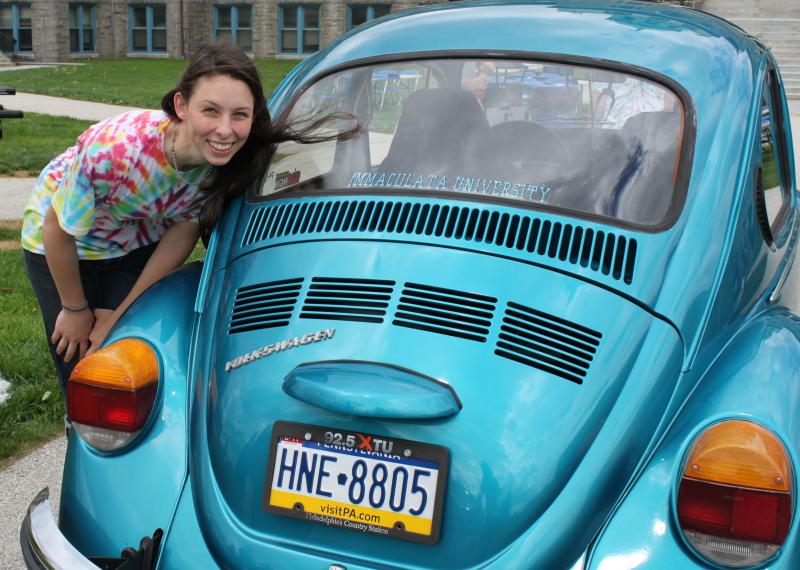 Student standing next to blue VW Beatle.