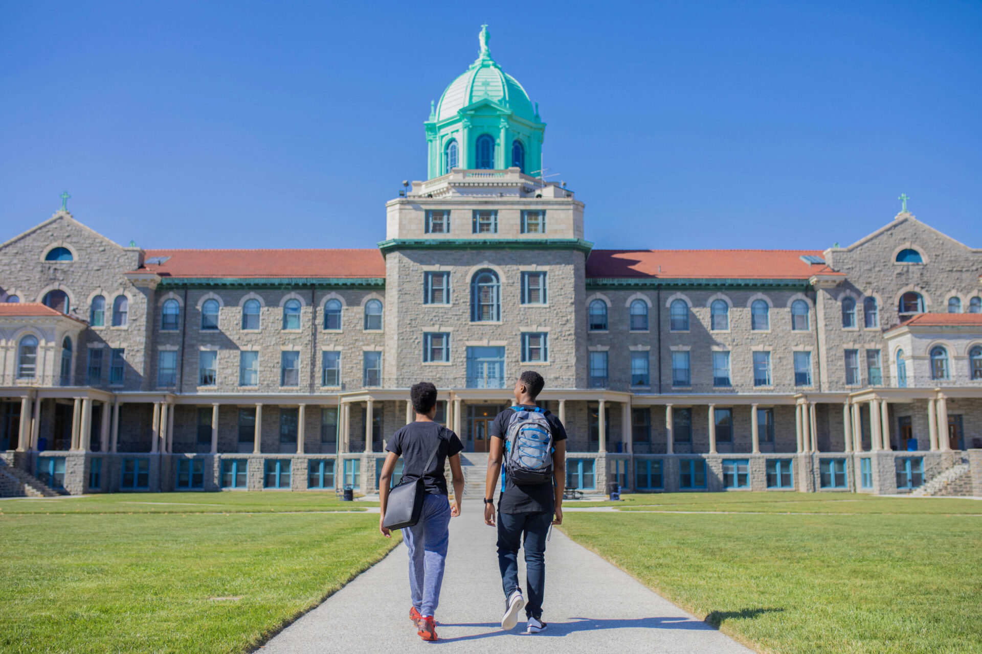 Two students walking in front of college building