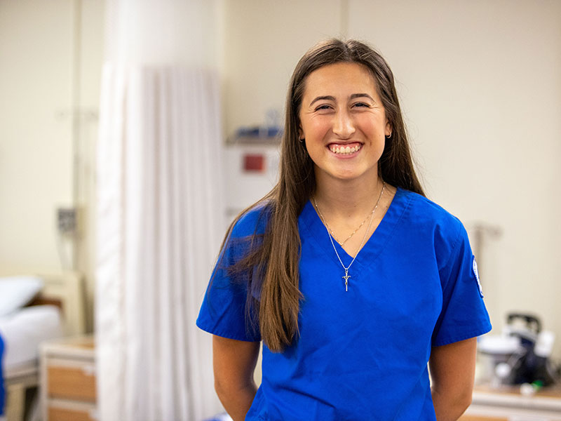 Woman in blue scrubs standing in nursing lab