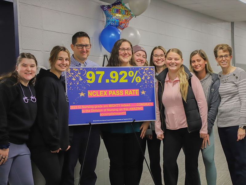 Nursing students and faculty with a sign showing the NCLEX pass rate