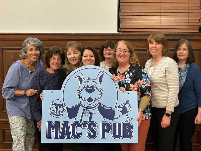Alumni holding sign "Mac's Pub"