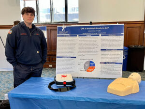 College student standing next to research poster.