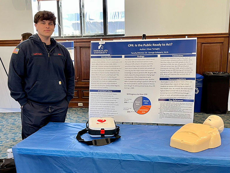 emt-day-1 College student standing next to research poster.