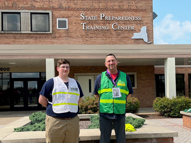 Two men in safety vests in front of NY State Preparedness Training Center