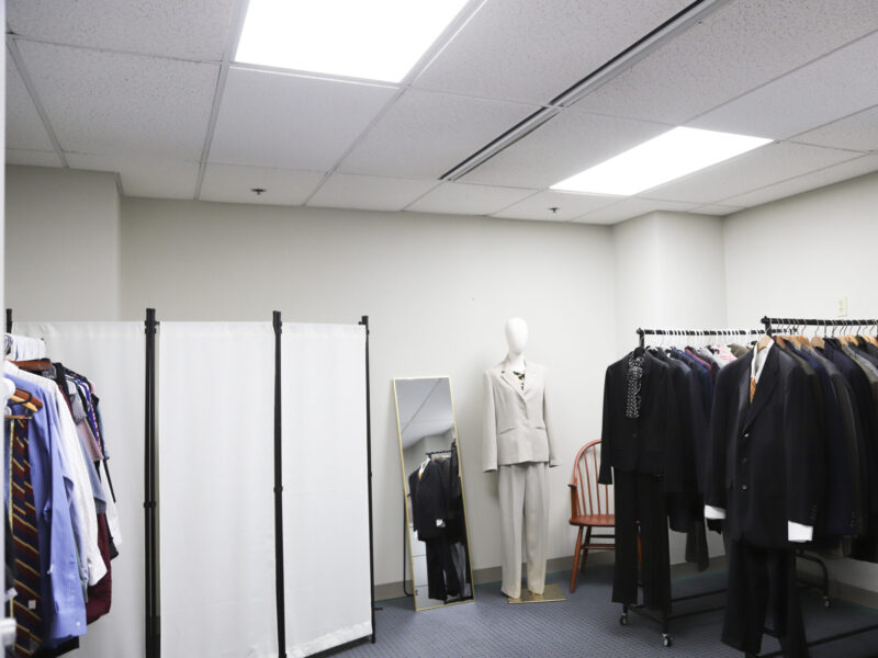 IMG_8811-3 Image of the Career Clothing Closet featuring racks of suits, blouses, skirts, dress pants, belts and ties, a private changing area and a mannequin displaying a women's suit.