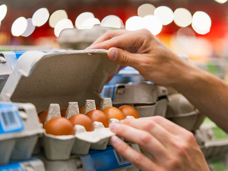 Person shopping for eggs at the grocery store.