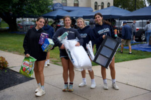 Young women carrying items to move into dorm