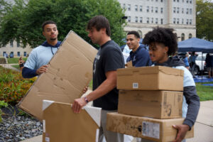 Young men carrying items to move into dorm