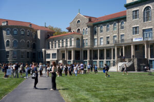 A crowd of students on college campus in front of old building