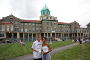 A young man and woman in front of a college building