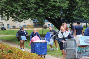 Young women carrying items to move into dorm