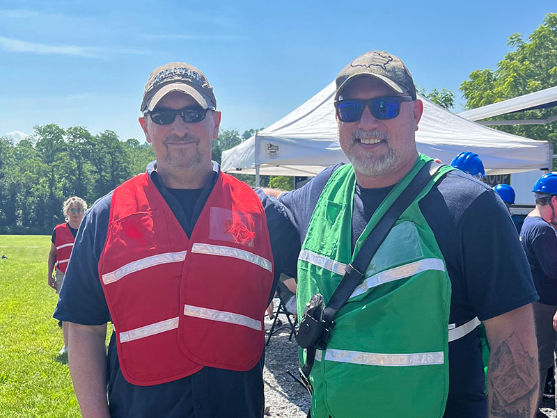 Two men wearing ball caps and safety vests