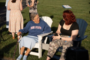 College student talking to nun, both in chairs outdoors