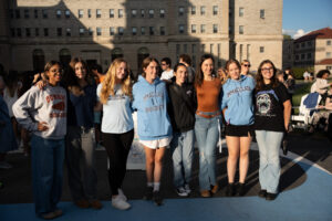 A group of college students standing outside in front of building