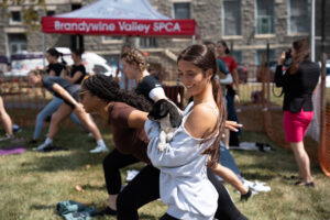 Young women doing yoga. One is holding a puppy.