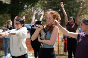 Young women doing yoga. One is holding a puppy.