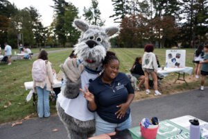 Costumed mascot Mac, a dog, waving with young woman