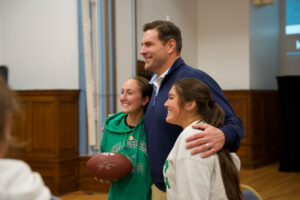 Large man with arm around two woemn