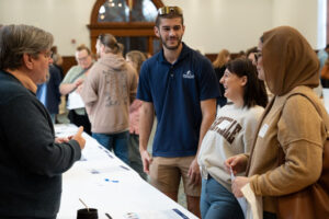 People at open house speaking to woman behind a table