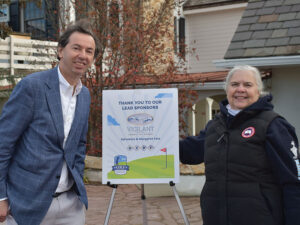A man and a woman next to sign that says "Thank you to our lead sponsors."