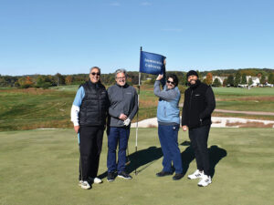 Four men on golf course holding flag