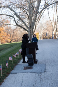 Speaker at a podium outside, in front of row of American flags