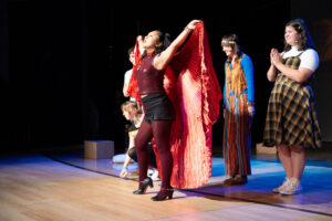 Actors on stage in costume (man and woman holding cape)