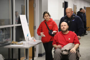 EMY wheeling patient down hall in wheelchair