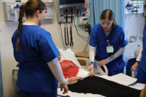 Nurses in scrubs with patient on bed