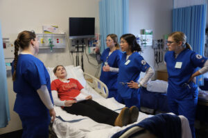 Nurses in scrubs with patient on bed
