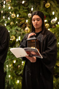 People in robes singing in front of Christmas tree