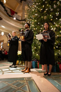 People in robes singing in front of Christmas tree