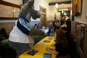 Mascot talks to women behind table