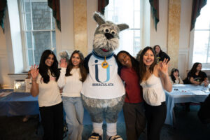 Mascot with arms around college students