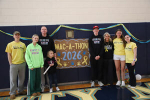 A group of people standing next to a banner that say "Mac-a-thon 2026."