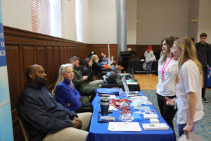 A group of people at a table talk to a student