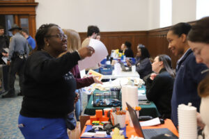 A woman at a table talks to a student