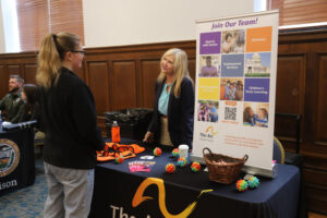 A woman at a table talks to a student
