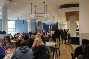 A large crowd of parents and students in a college dining hall
