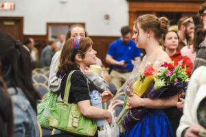 Young woman holding flowers talking to another woman