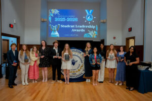 Group of students posing with leadership awards on stage during a university ceremony.