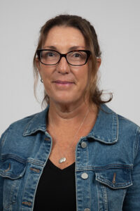 Butler-Aungst_Denise - Immaculata University Portrait of a woman with brown hair and glasses wearing a denim jacket, looking at the camera.