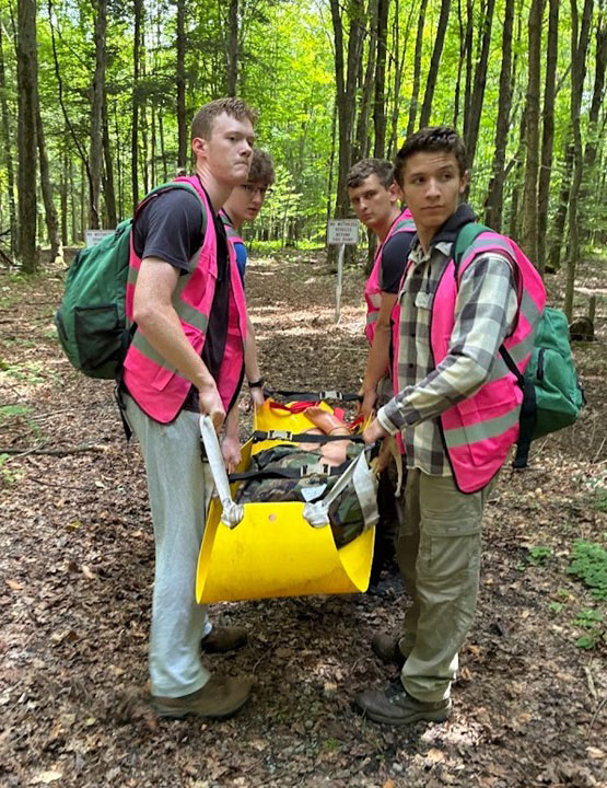 Joe-Dilauro - Immaculata University Four men wearing safety vests and carrying a hiker in a stretcher