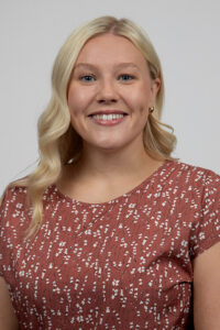Lorimer_Emily - Immaculata University Portrait of a smiling blonde woman wearing a pink patterned blouse.