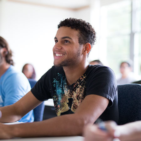 Academic Advising at Immaculata University - male student at desk in classroom smiling