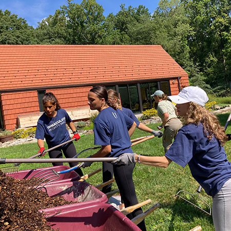 Student Service and Mission at Immaculata - 3 students working at a grounds cleanup project