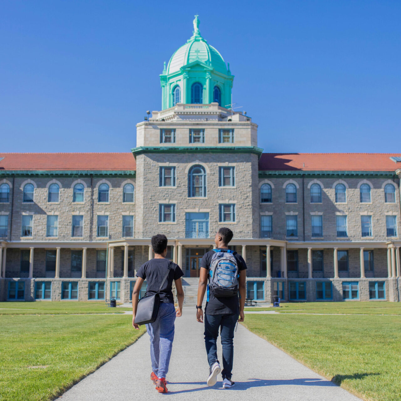 Two students walking in front of college building